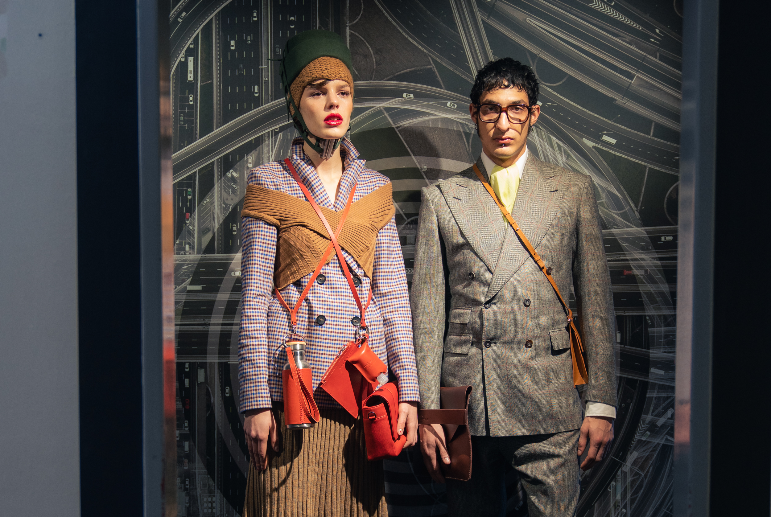 Two models wearing a blazer by Lanius, trousers & skirt by Fassbender, top by Studio Fantastique, knitted hat by Pugnat, hat by Spatz Hutdesign, bag & bottle by Trakatan, handbag by Alexandra Svendsen and shoes Miu Miu at Nightboutique Archive as well as a suit, handkerchief & collar by Maximilian Mogg, shirt by G-Star Raw, clutch by Agnes Nordenholz, crossbody bag by Alinaschuerfeld, glasses by Andy Wolf and shoes by Salvatore Ferragamo Vintage at Neonyt Installation