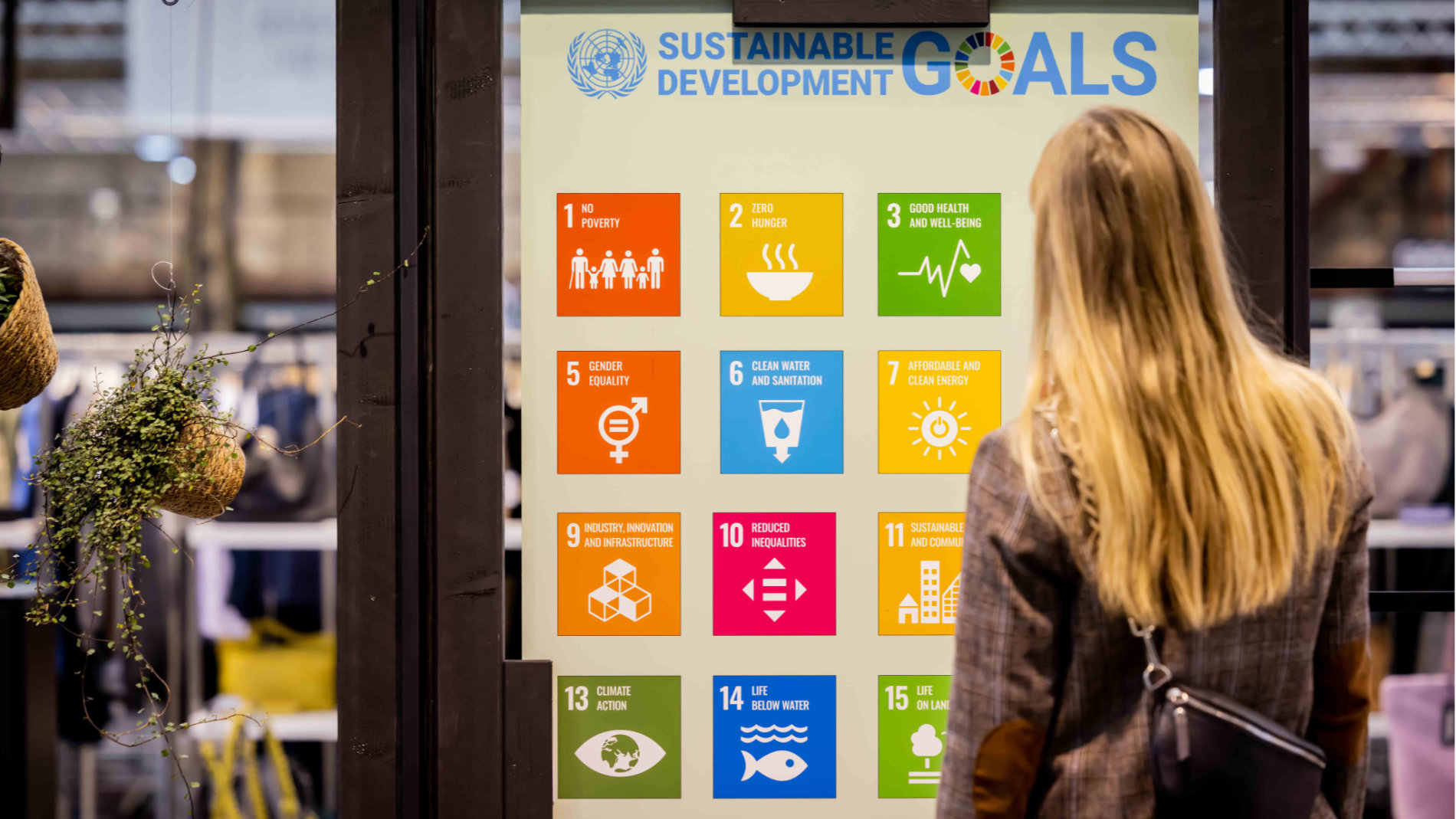 Woman in front of a poster on SDGs at Neonyt in Düsseldorf 2023
